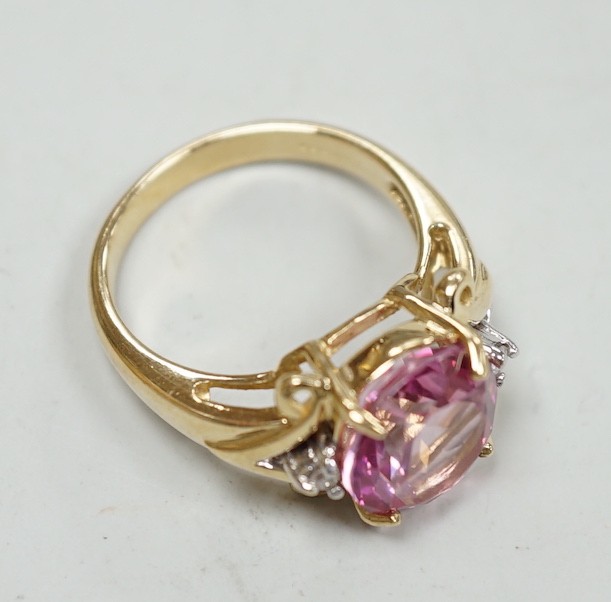 A modern 9ct gold and single stone oval cut flamingo topaz dress ring with two stone diamond set shoulders, size N, gross weight 5.3 grams, with Gems TV certificate.